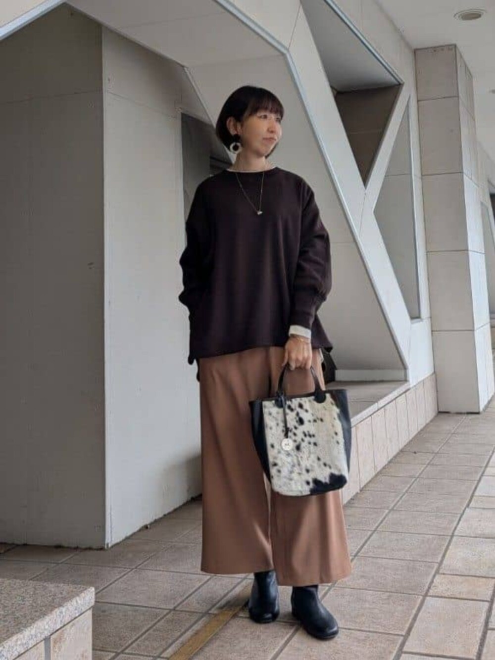 ブラック系のブーツ、ブラウン系のTシャツ/カットソー、ブラウン系のトートバッグを着用したレディースの冬コーディネートの1枚目の写真
