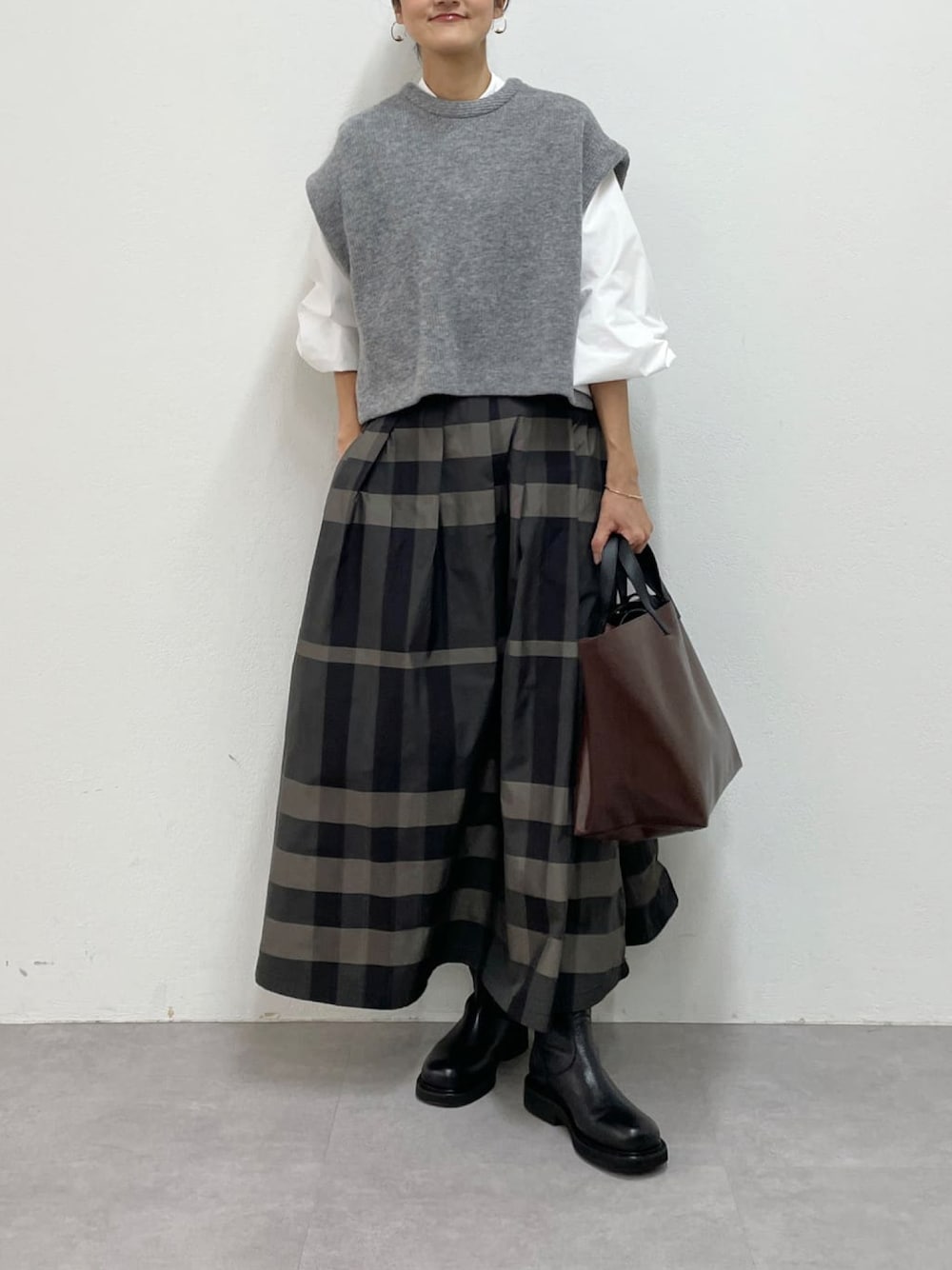 グレー系のスカート、ブラック系のブーツを着用したレディースの冬コーディネートの1枚目の写真