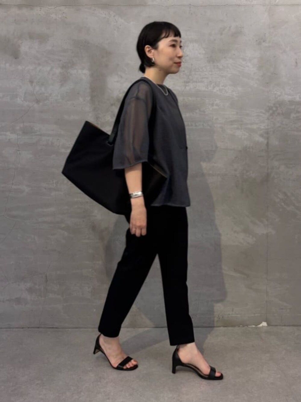 ブラック系のその他パンツ、グレー系のシャツ/ブラウス、ブラック系のトートバッグを着用したレディースの春コーディネートの1枚目の写真