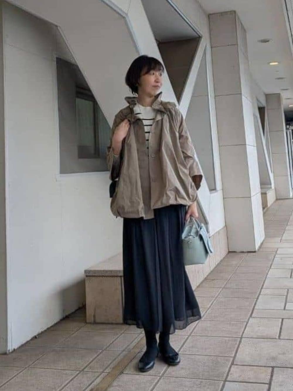 グリーン系のハンドバッグ、ブラック系のその他パンツ、ブラウン系のブルゾンを着用したレディースの冬コーディネートの1枚目の写真