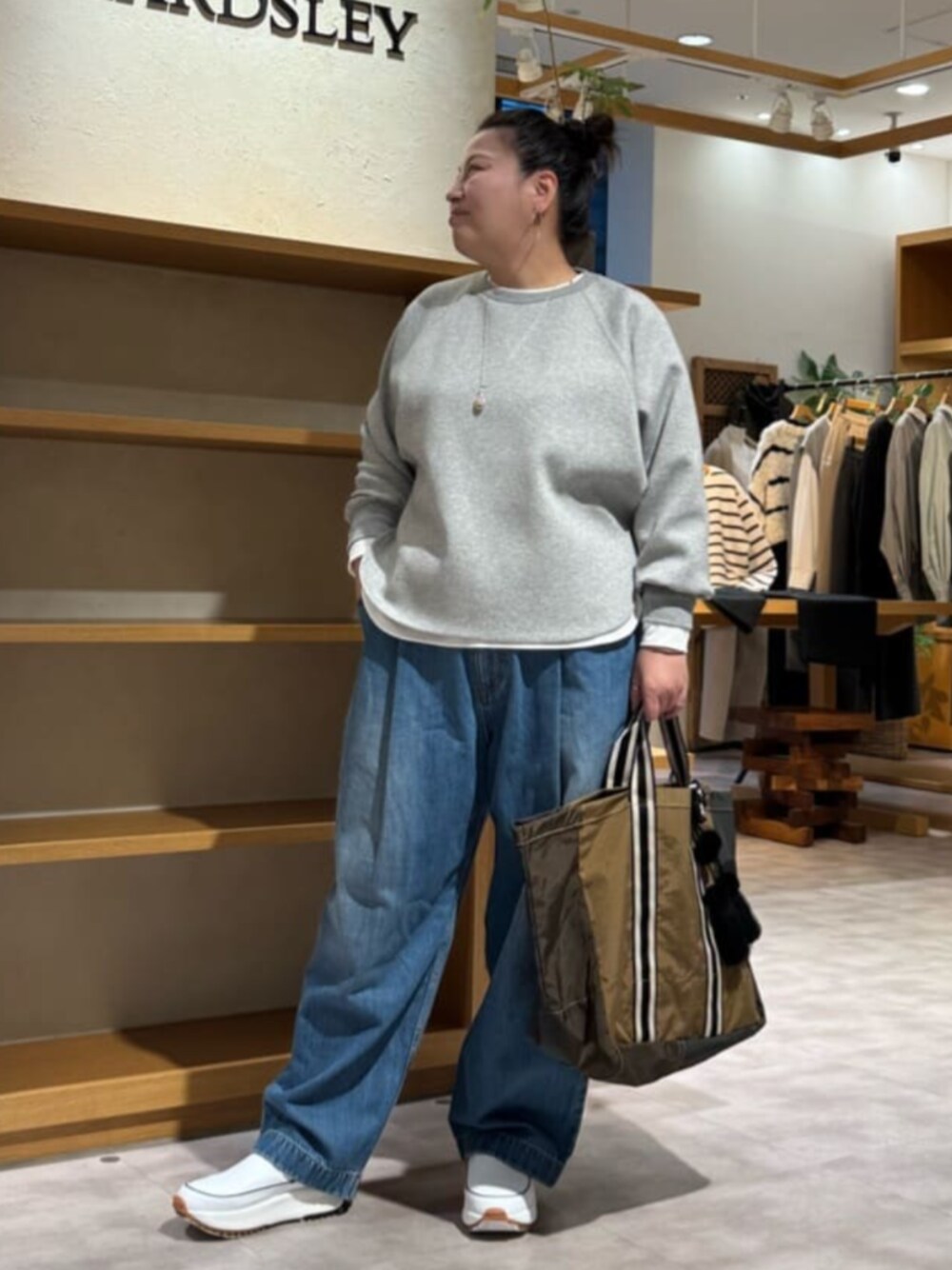 ブルー系のデニムパンツ、グレー系のTシャツ/カットソー、イエロー系のトートバッグを着用したレディースの秋コーディネートの1枚目の写真