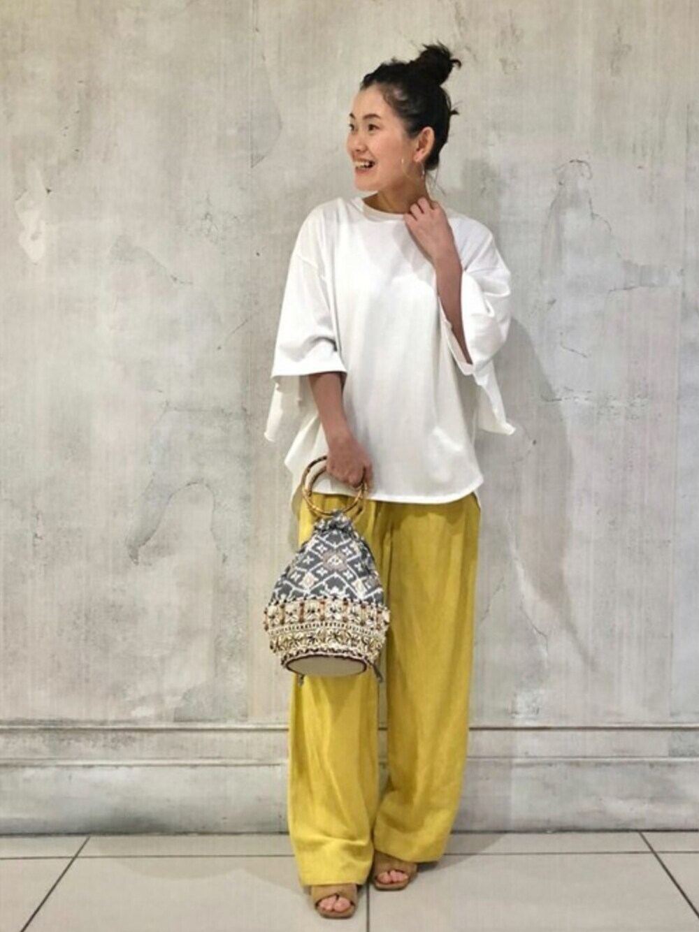 ホワイト系のTシャツ/カットソー、イエロー系のその他パンツ、ベージュ系のハンドバッグを着用したレディースの夏コーディネートの1枚目の写真