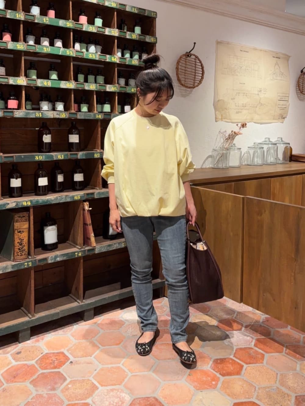 ブルー系のデニムパンツ、イエロー系のTシャツ/カットソー、ブラウン系のトートバッグを着用したレディースの冬コーディネートの1枚目の写真