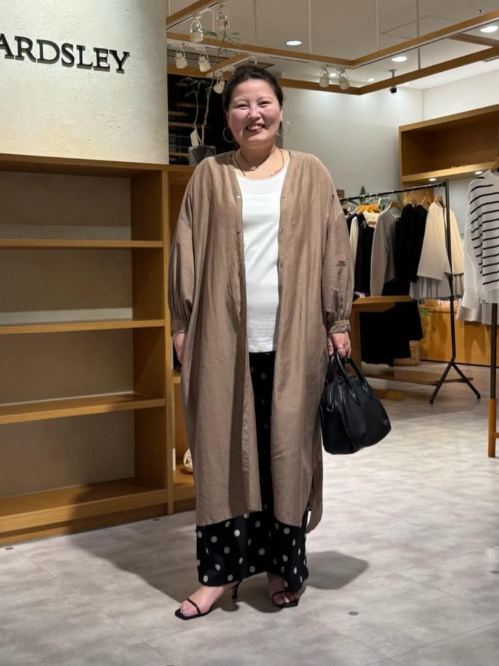 ブラック系のボストンバッグ、ベージュ系のワンピース、ブラック系のその他パンツを着用したレディースの冬コーディネートの1枚目の写真