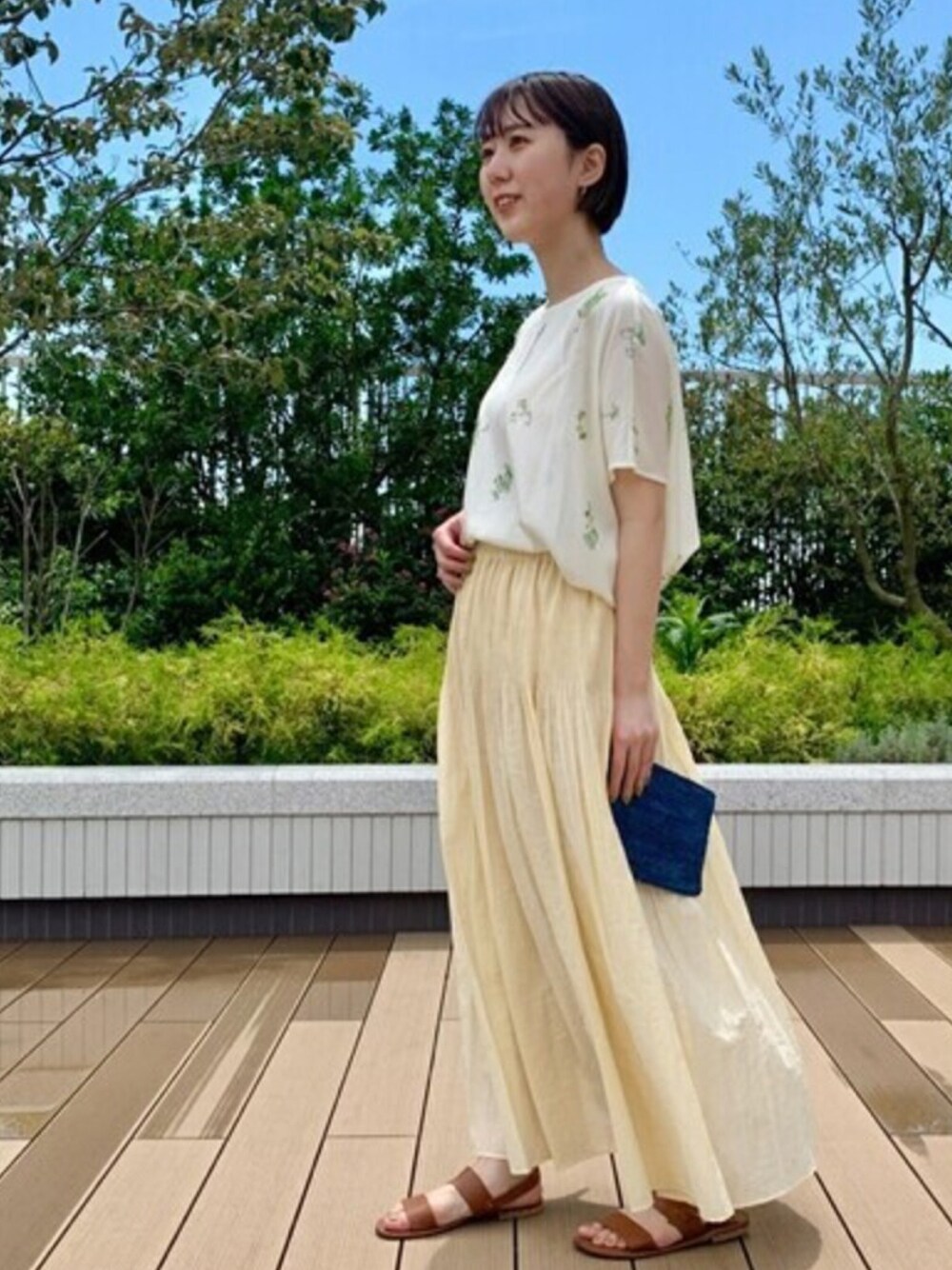 ホワイト系のシャツ/ブラウス、イエロー系のスカート、ブラウン系のサンダルを着用したレディースの夏コーディネートの1枚目の写真