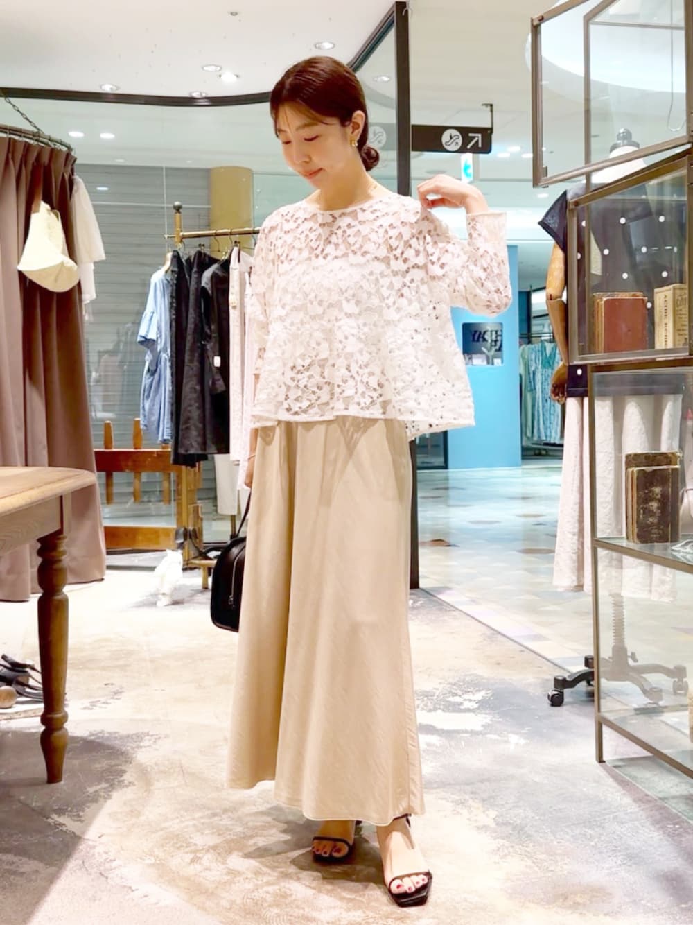 ホワイト系のシャツ/ブラウス、ベージュ系のスカート、ブラック系のトートバッグを着用したレディースの夏コーディネートの1枚目の写真