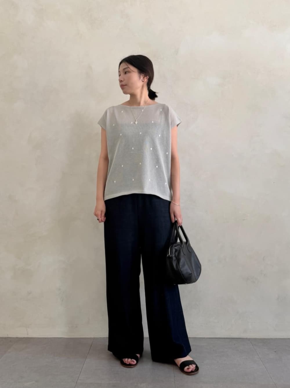ブルー系のその他パンツ、ブラック系のボストンバッグ、グレー系のニット/セーターを着用したレディースの春コーディネートの1枚目の写真