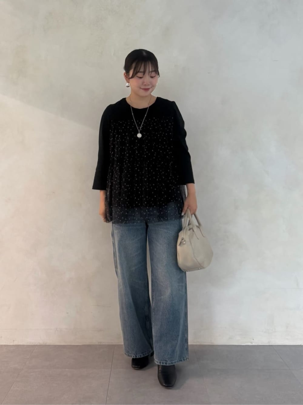 グレー系のボストンバッグ、ブラック系のTシャツ/カットソー、ブルー系のデニムパンツを着用したレディースの夏コーディネートの1枚目の写真