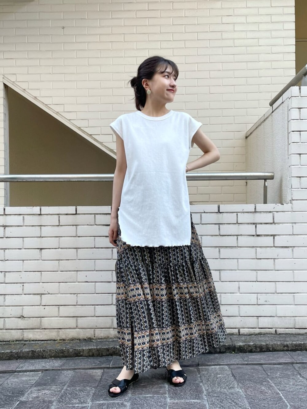 ホワイト系のTシャツ/カットソー、ブラック系のスカート、ブラック系のサンダルを着用したレディースの夏コーディネートの1枚目の写真