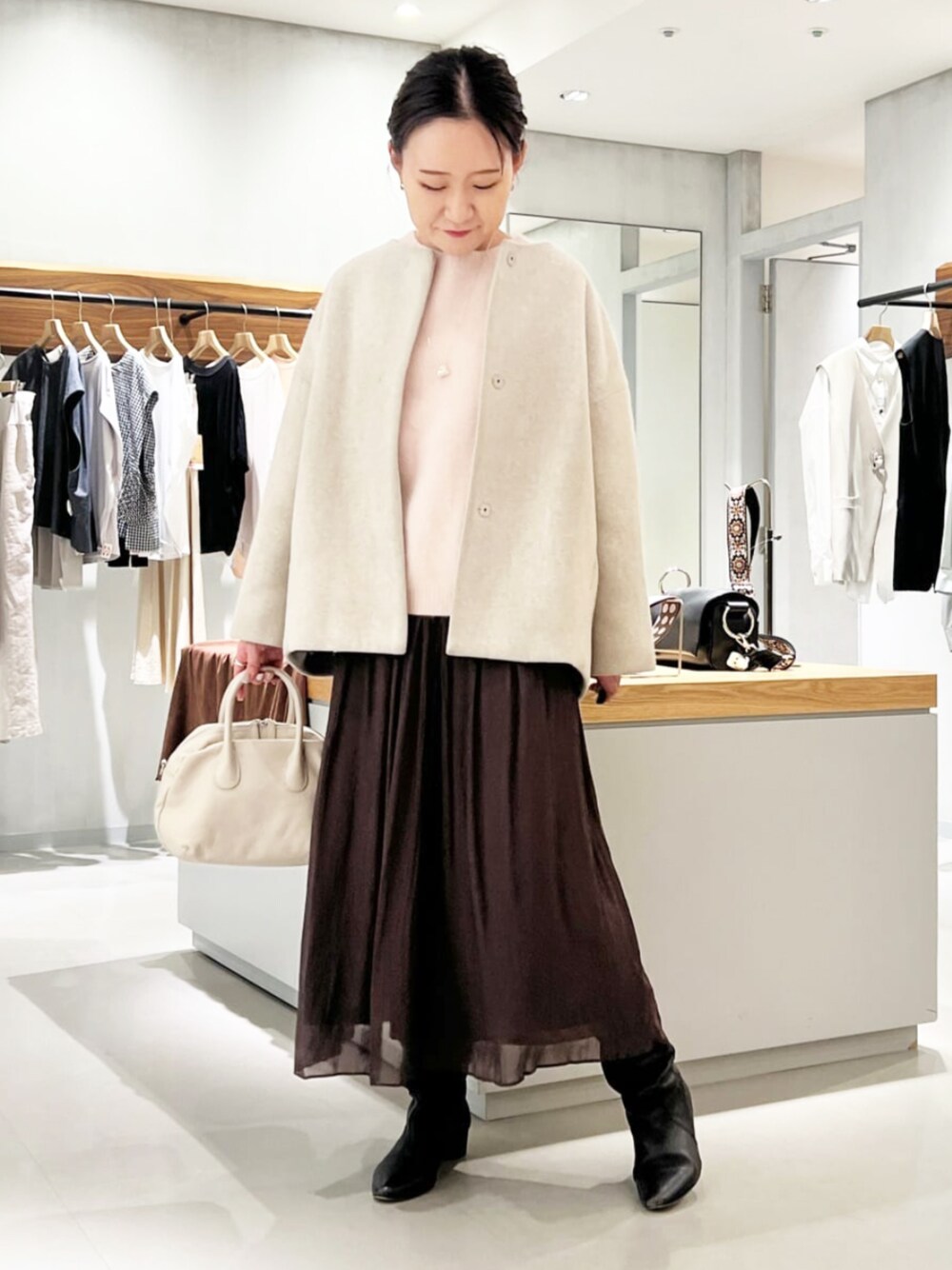 グレー系のボストンバッグ、グレー系のノーカラーコート、ブラウン系のその他パンツを着用したレディースの秋コーディネートの1枚目の写真