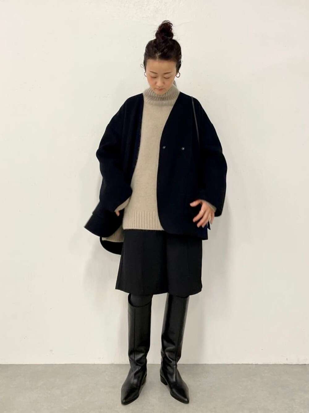 ブラック系のその他パンツ、ブラック系のノーカラーコート、グリーン系のニット/セーターを着用したレディースの秋コーディネートの1枚目の写真