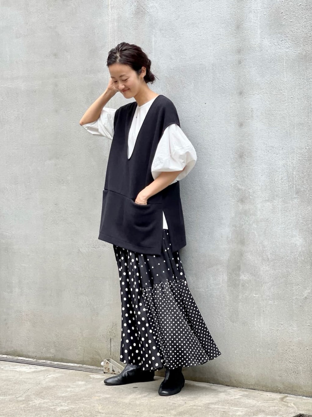 ブラック系のスカート、ホワイト系のシャツ/ブラウス、ブラック系のブーツを着用したレディースの夏コーディネートの1枚目の写真