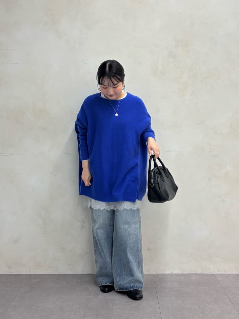 ブラック系のトートバッグ、ブルー系のデニムパンツ、ブラック系のブーツを着用したレディースの秋コーディネートの1枚目の写真
