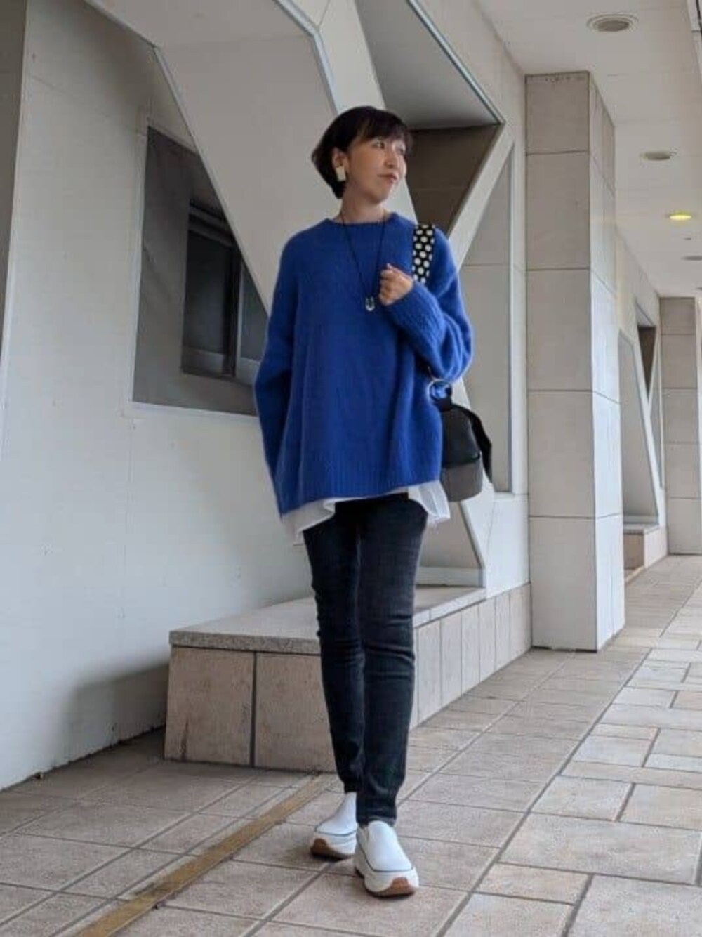 ホワイト系のTシャツ/カットソー、ホワイト系のスニーカー、ブルー系のニット/セーターを着用したレディースの冬コーディネートの1枚目の写真