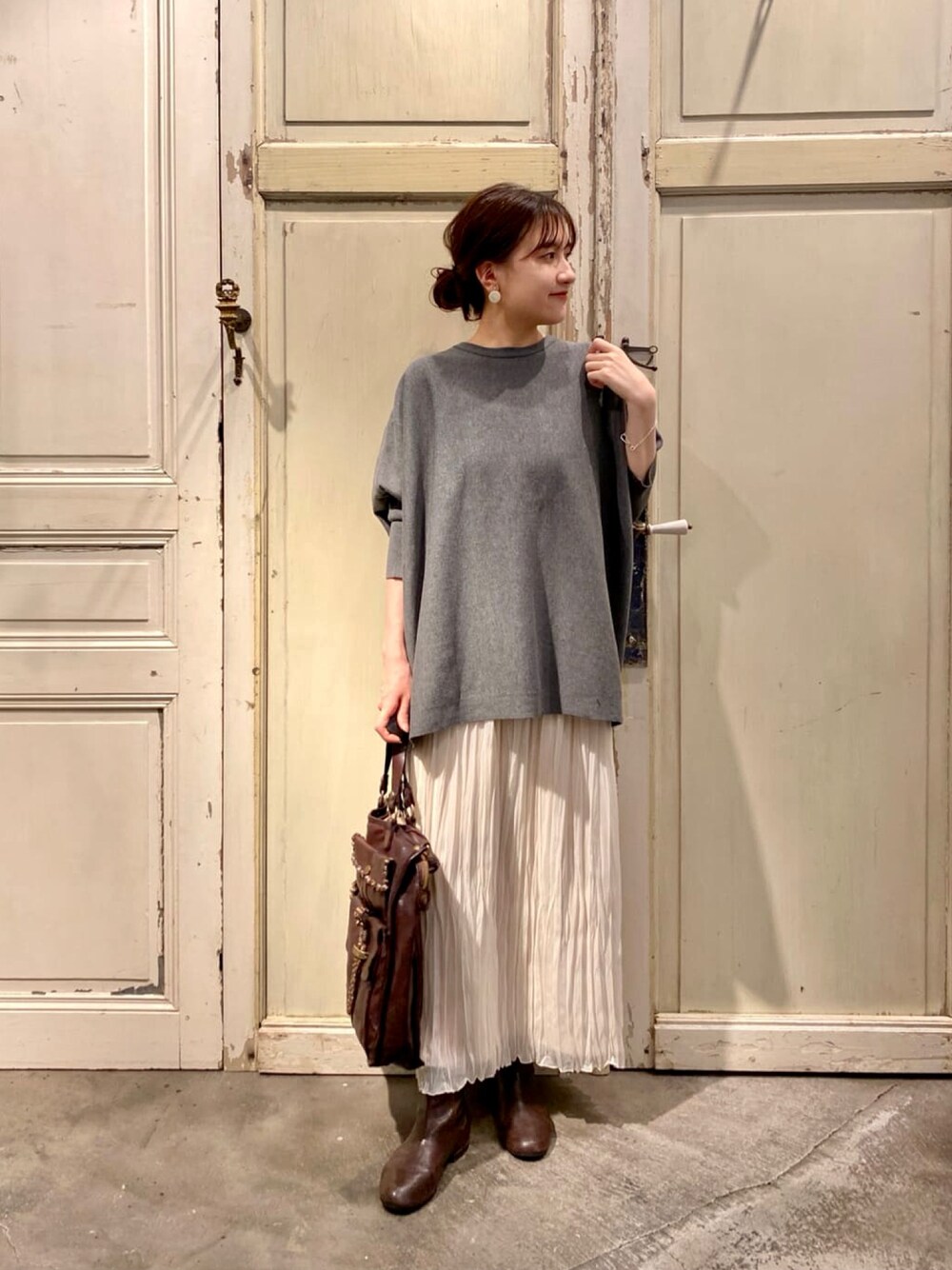 グレー系のニット/セーター、ホワイト系のスカート、ブラウン系のブーツを着用したレディースの秋コーディネートの1枚目の写真