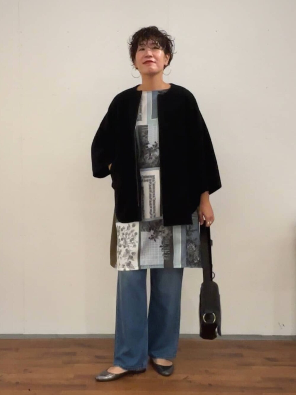 ブラック系のその他アウター、ブルー系のデニムパンツ、グリーン系のワンピースを着用したレディースの秋コーディネートの1枚目の写真