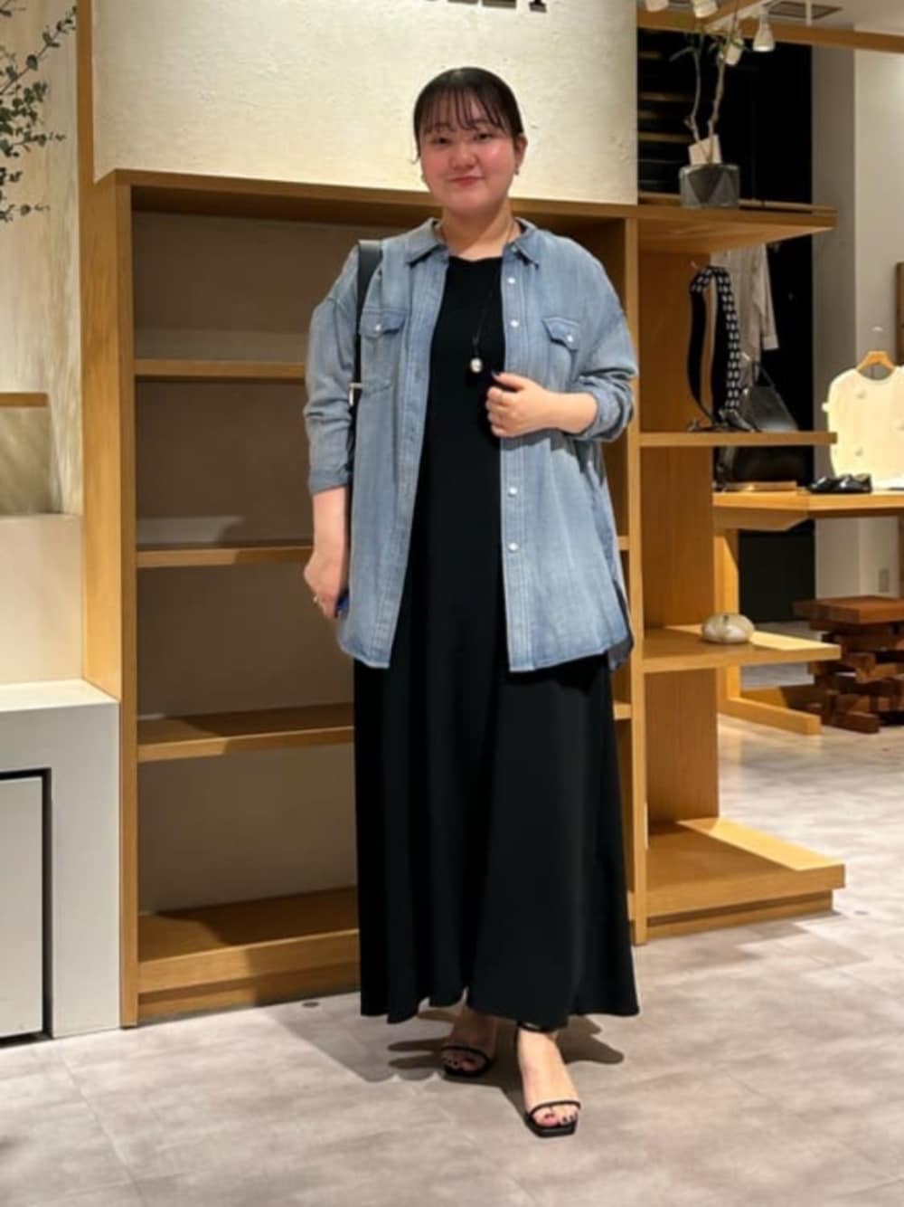 ブルー系のシャツ/ブラウス、ブラック系のワンピースを着用したレディースの春コーディネートの1枚目の写真