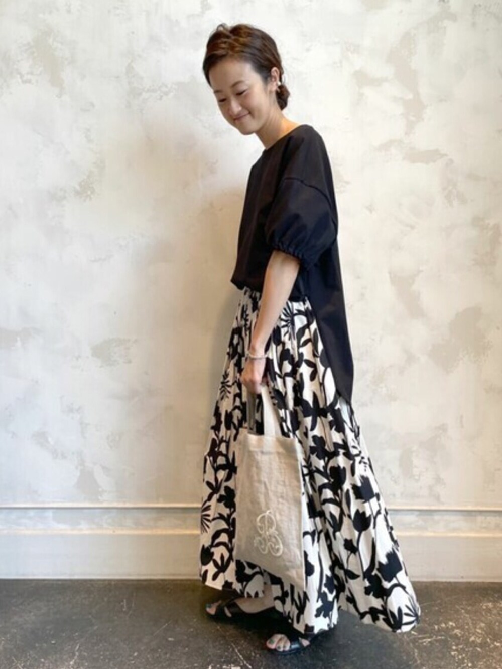 ブラック系のTシャツ/カットソー、ベージュ系のスカート、ベージュ系のトートバッグを着用したレディースの夏コーディネートの1枚目の写真