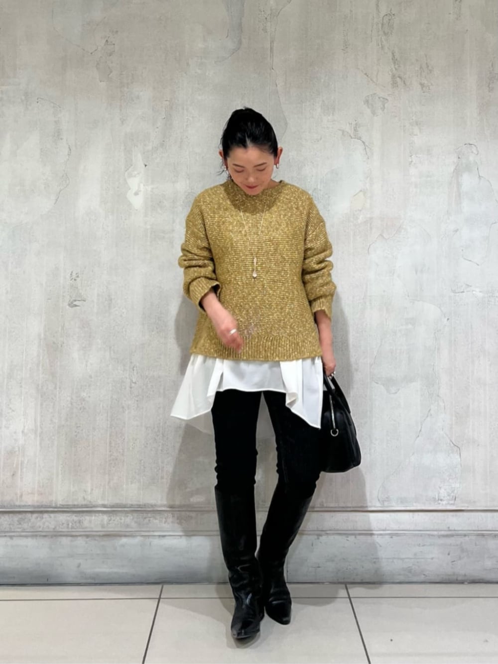 ホワイト系のTシャツ/カットソー、イエロー系のニット/セーター、ブルー系のデニムパンツを着用したレディースの冬コーディネートの1枚目の写真