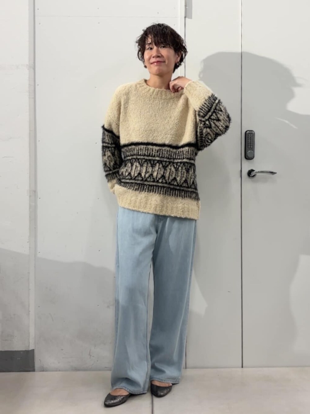 ブルー系のデニムパンツ、ベージュ系のニット/セーターを着用したレディースの秋コーディネートの1枚目の写真