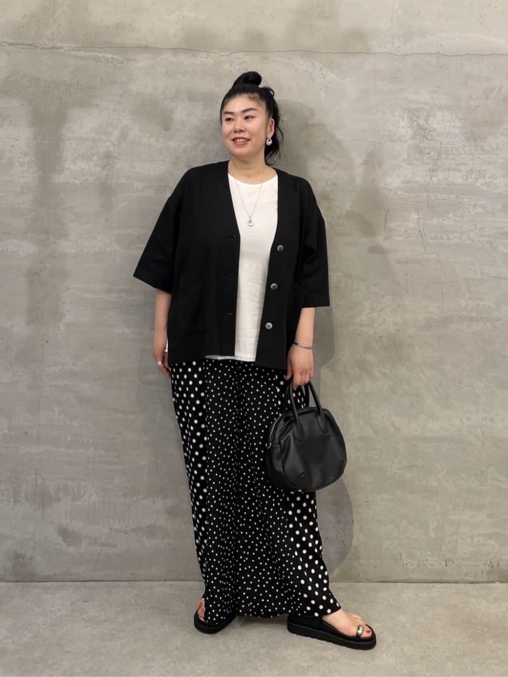 ホワイト系のタンクトップ、ブラック系のボストンバッグ、ブラック系のサンダルを着用したレディースの春コーディネートの1枚目の写真