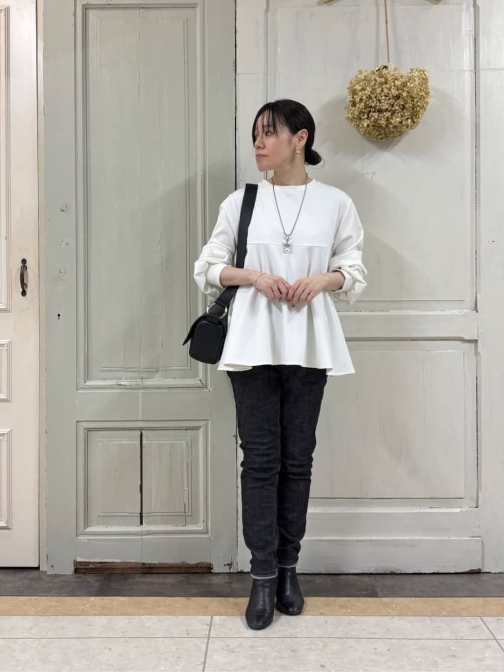 ブラック系のショルダーバッグ、ブラック系のデニムパンツ、ホワイト系のTシャツ/カットソーを着用したレディースの冬コーディネートの1枚目の写真