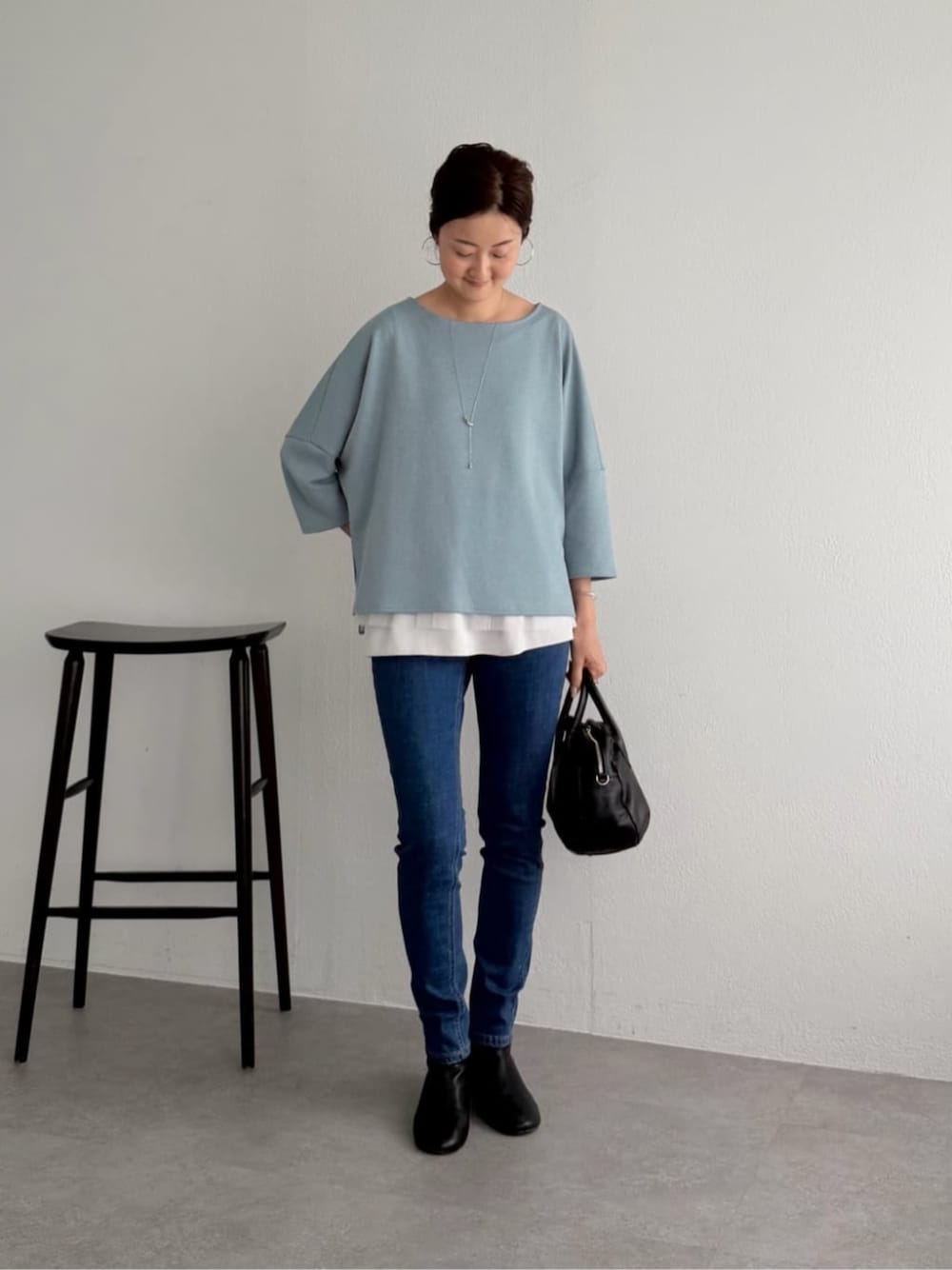 ブルー系のデニムパンツ、ブルー系のニット/セーター、ホワイト系のキャミソールを着用したレディースの夏コーディネートの1枚目の写真