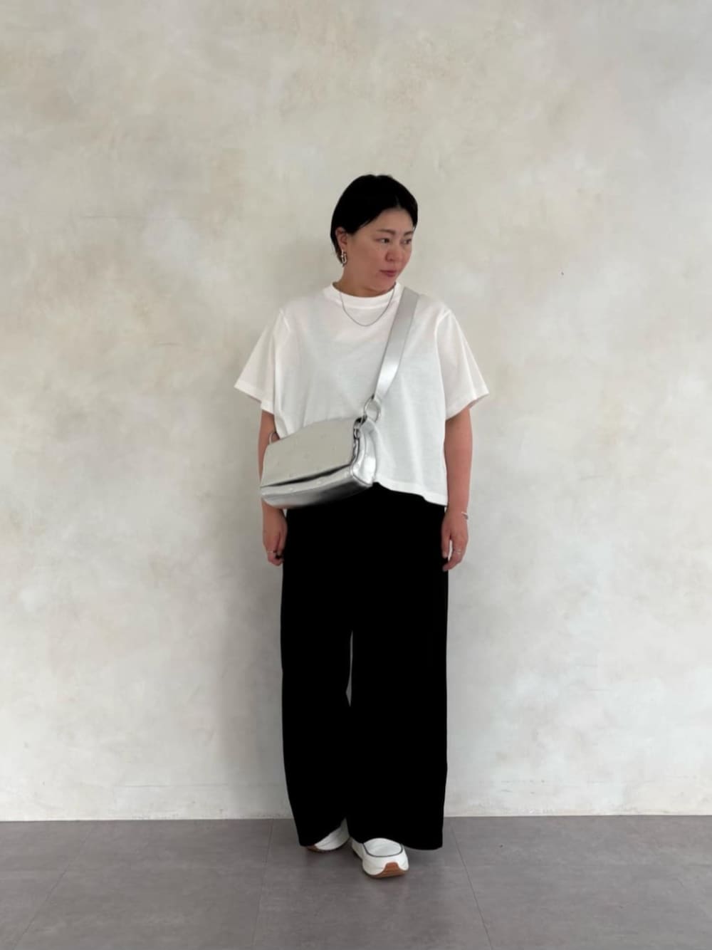 シルバー系のショルダーバッグ、ホワイト系のTシャツ/カットソー、ホワイト系のスニーカーを着用したレディースの春コーディネートの1枚目の写真