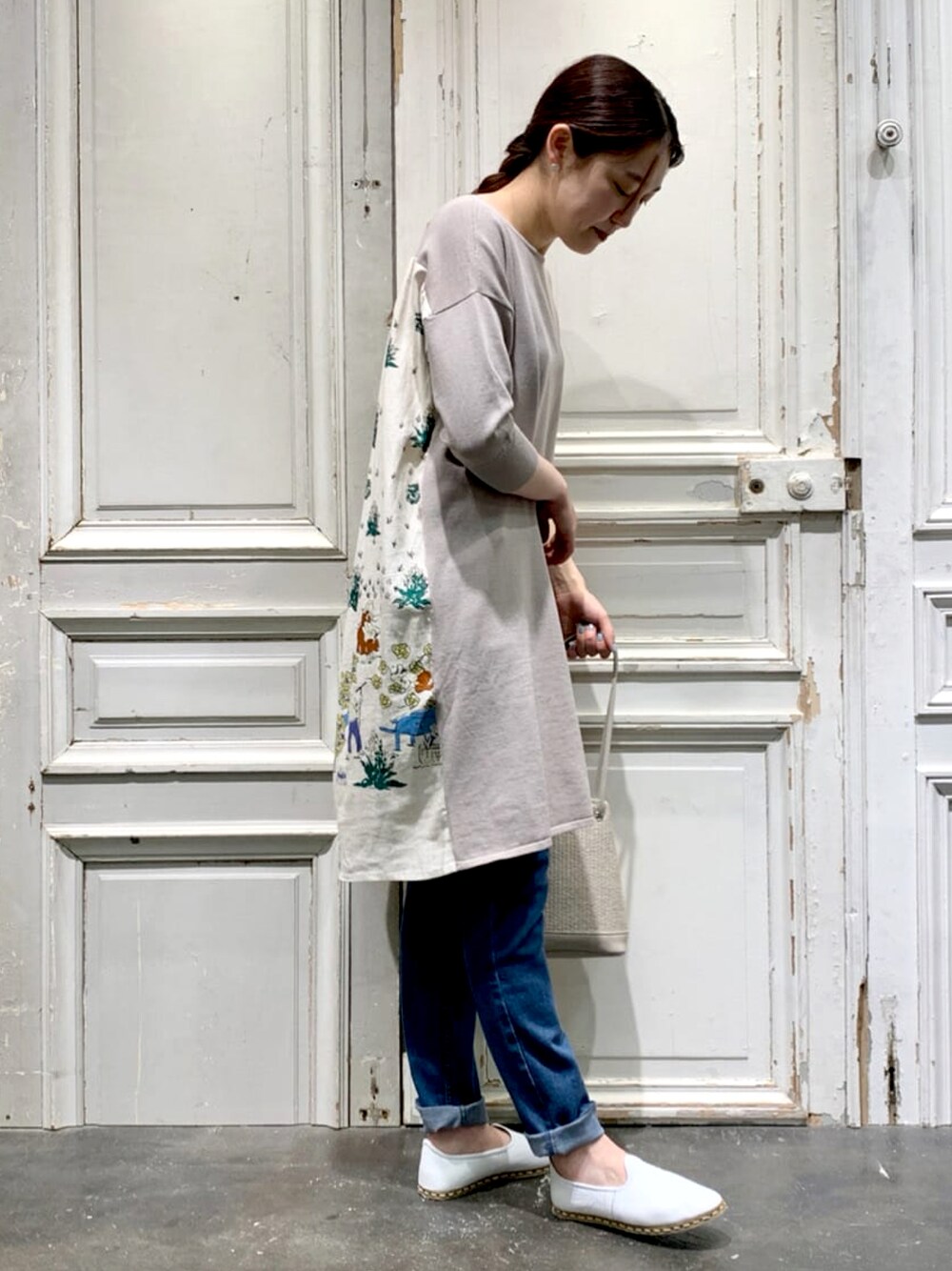 ベージュ系のニット/セーター、ブルー系のデニムパンツ、ベージュ系のトートバッグを着用したレディースの春コーディネートの1枚目の写真