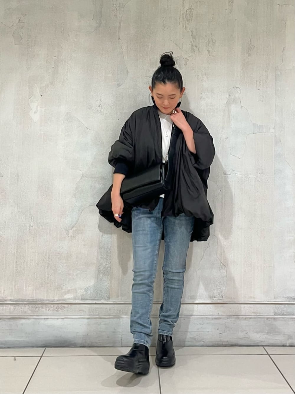 ブルー系のデニムパンツ、ブラック系のショルダーバッグ、ブラック系のその他アウターを着用したレディースの冬コーディネートの1枚目の写真