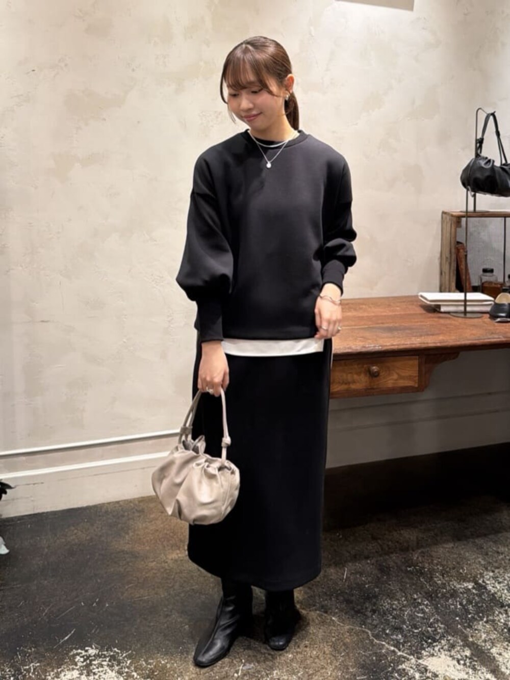 ベージュ系のショルダーバッグ、ホワイト系のシャツ/ブラウス、ブラック系のTシャツ/カットソーを着用したレディースの冬コーディネートの1枚目の写真