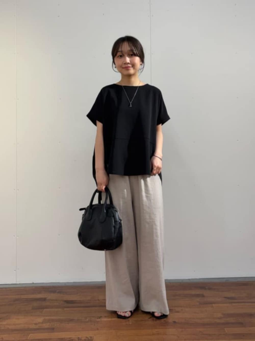 ブラック系のボストンバッグ、ブラック系のシャツ/ブラウス、グレー系のその他パンツを着用したレディースの春コーディネートの1枚目の写真