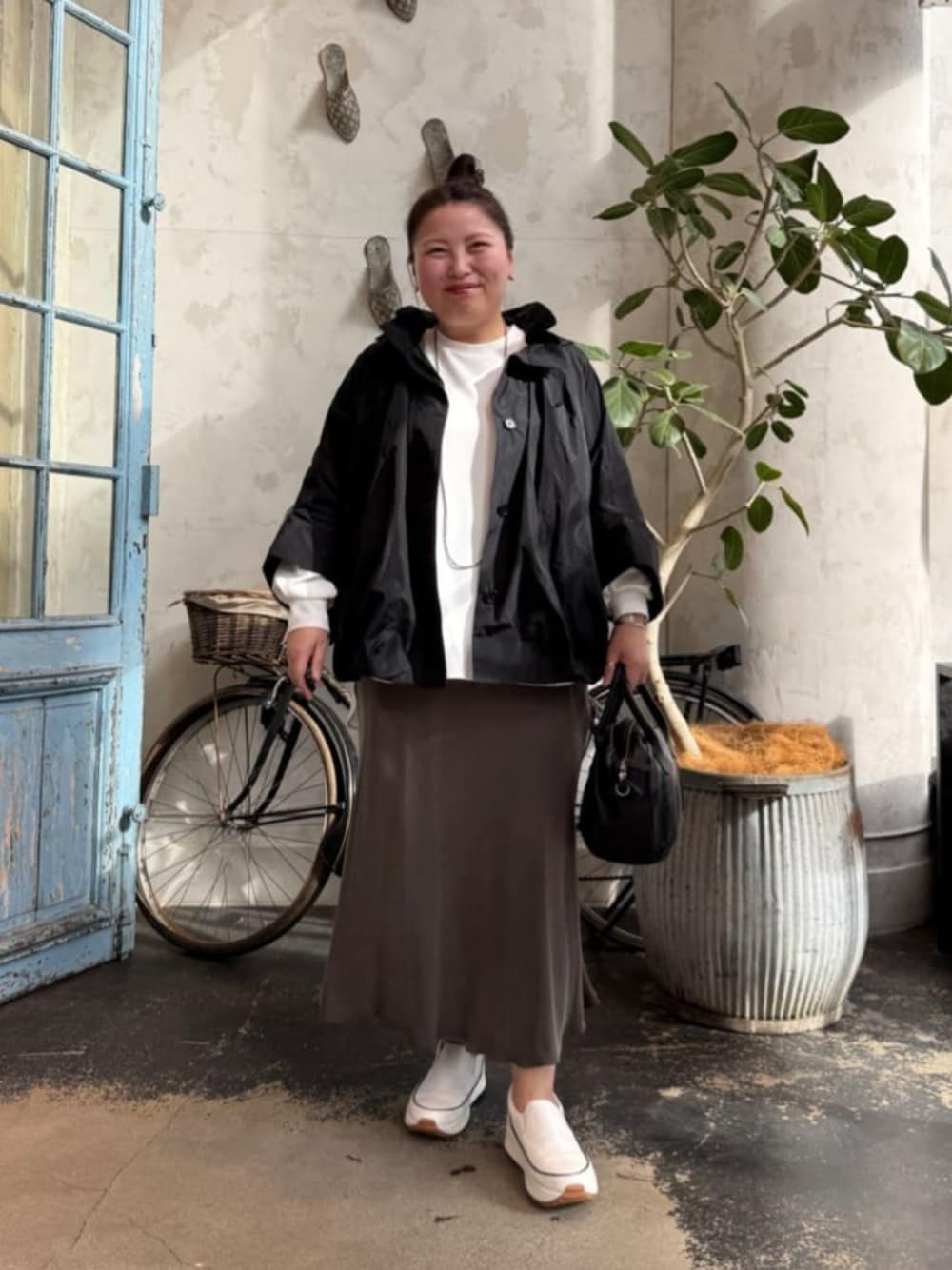 グリーン系のスカート、ブラック系のボストンバッグ、ホワイト系のシャツ/ブラウスを着用したレディースの冬コーディネートの1枚目の写真