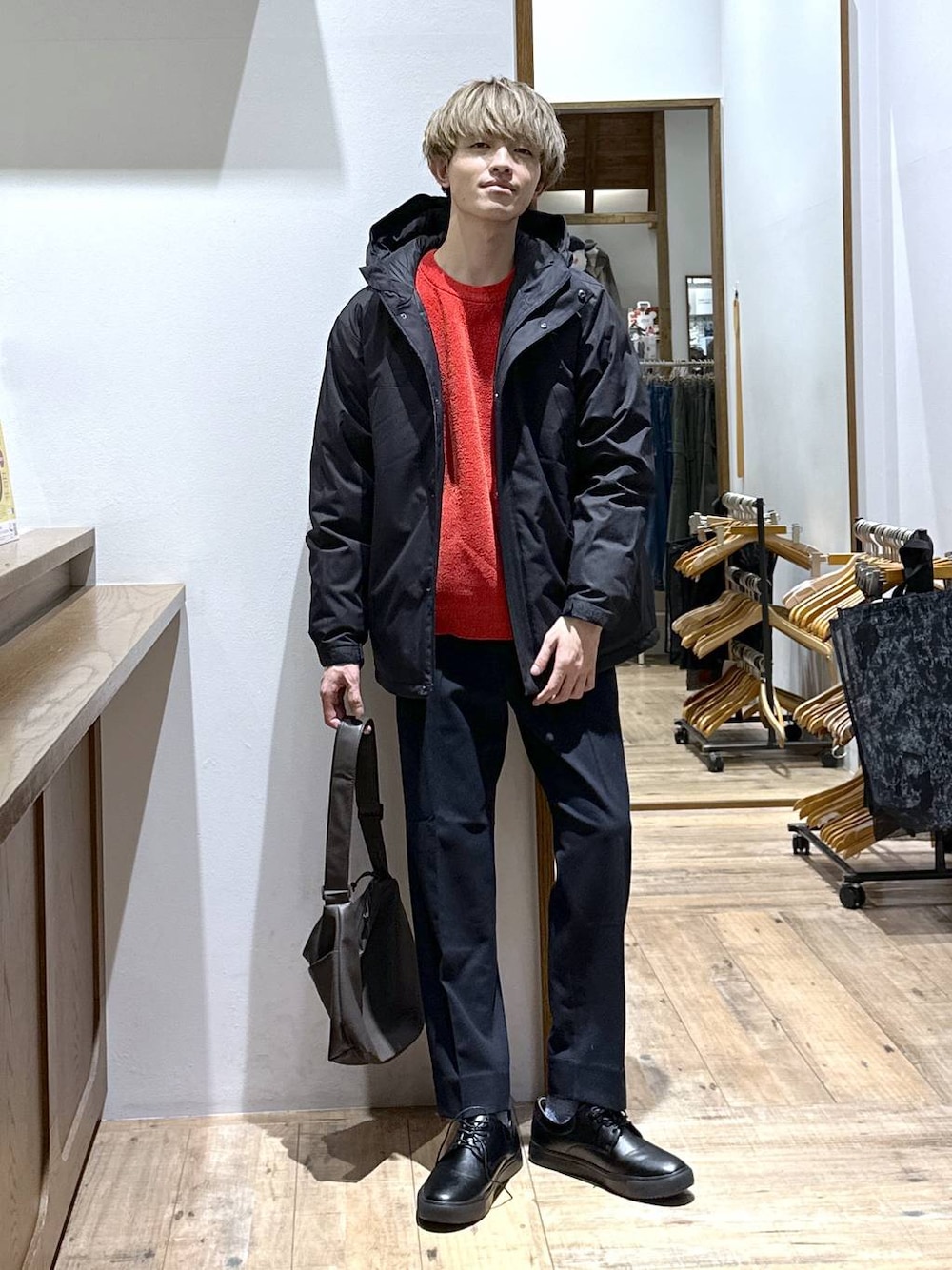 ブラック系のダウンジャケット/コート、ブルー系のスラックス、レッド系のニット/セーターを着用したメンズの冬コーディネートの1枚目の写真