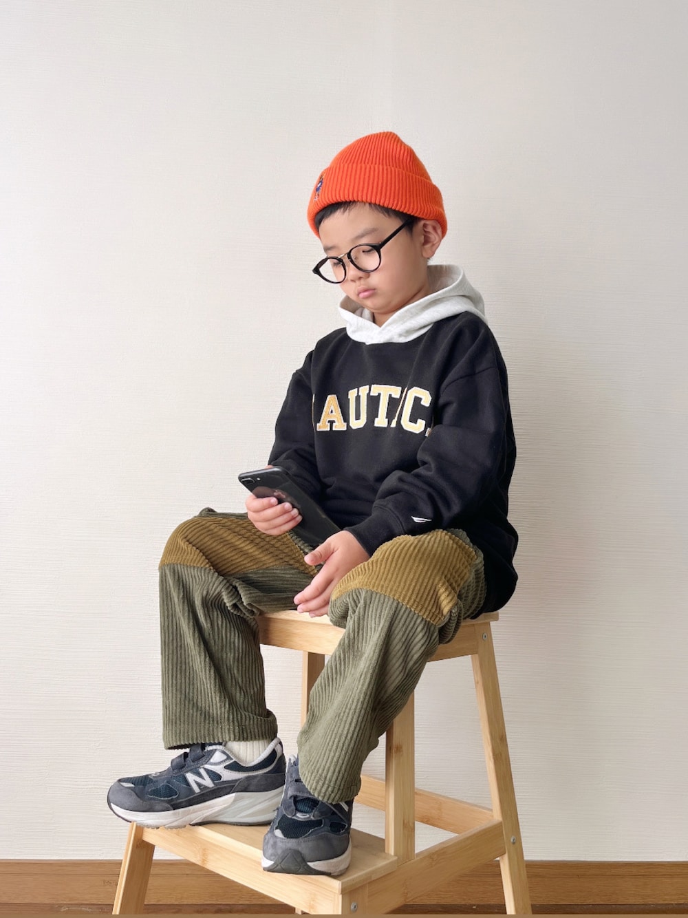 ブラック系のパーカー、グリーン系のカーゴパンツ、ブルー系のスニーカーを着用したキッズの冬コーディネートの1枚目の写真