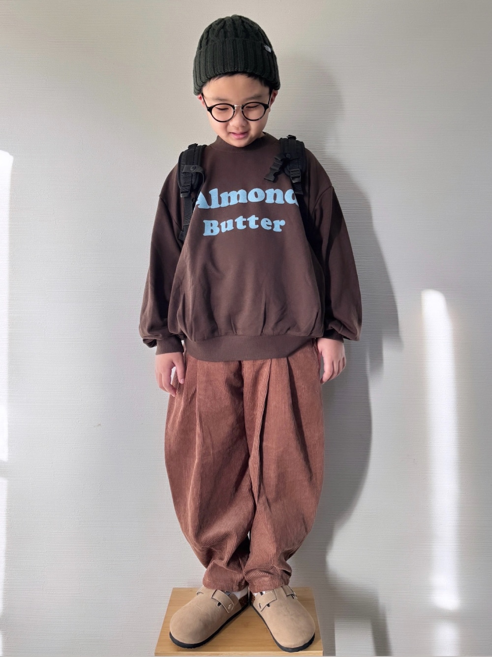 ブラウン系のスウェット、ブラウン系のその他パンツ、ベージュ系のサンダルを着用したキッズの冬コーディネートの1枚目の写真