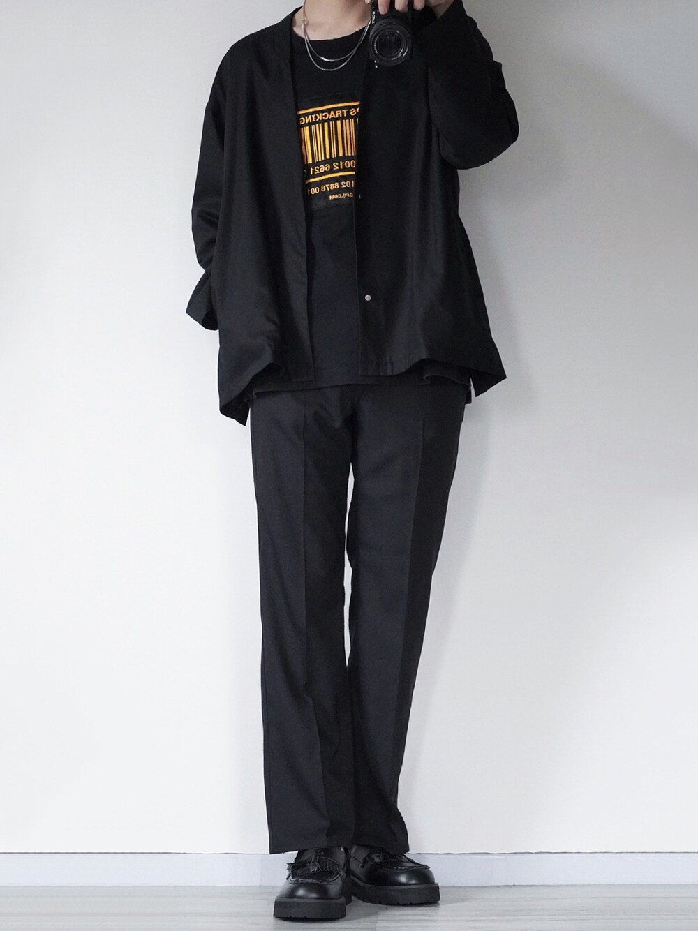 ブラック系のノーカラージャケット、ブラック系のTシャツ/カットソー、ブラック系のスラックスを着用したメンズの春コーディネートの1枚目の写真