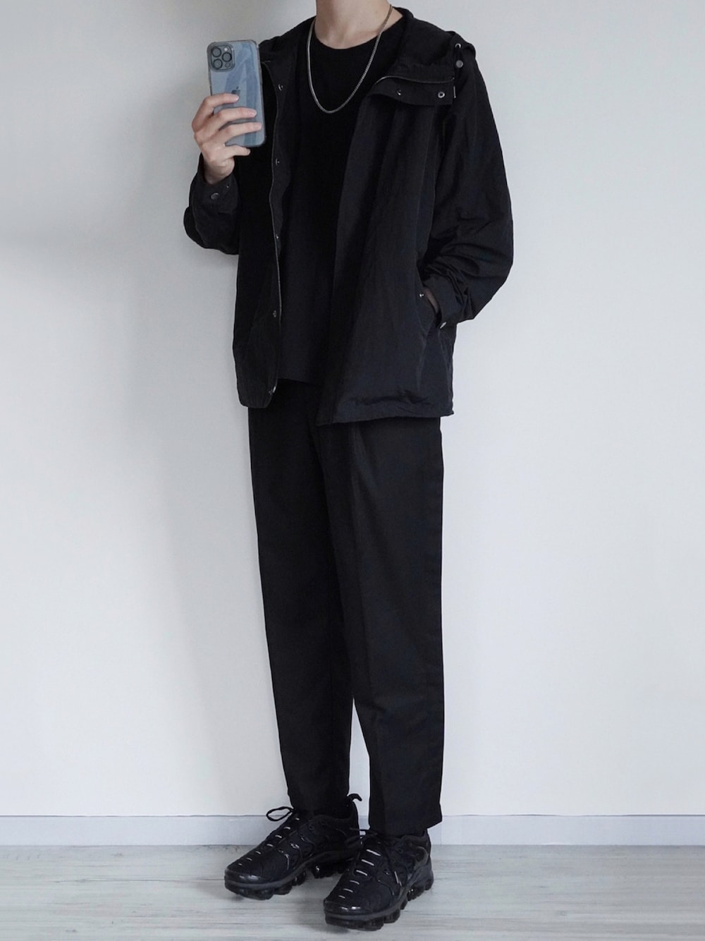 ブラック系のマウンテンパーカー、ブラック系のTシャツ/カットソー、ブラック系のスラックスを着用したメンズの秋コーディネートの1枚目の写真