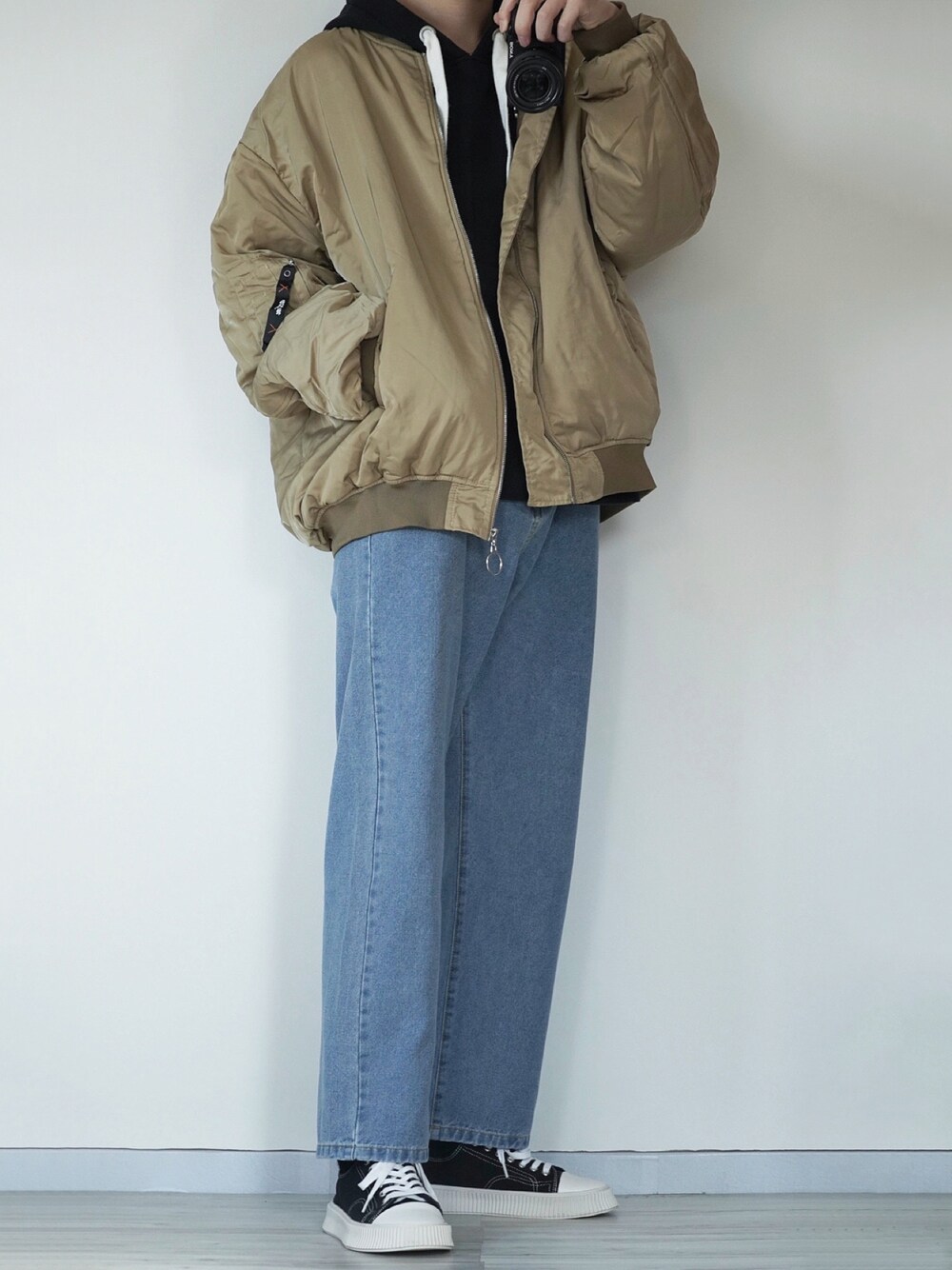 ブルー系のデニムパンツ、ベージュ系のMA-1、ブラック系のパーカーを着用したメンズの冬コーディネートの1枚目の写真