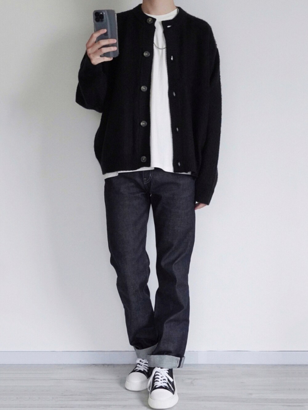 ブラック系のカーディガン/ボレロ、ホワイト系のTシャツ/カットソー、ブラック系のデニムパンツを着用したメンズの秋コーディネートの1枚目の写真