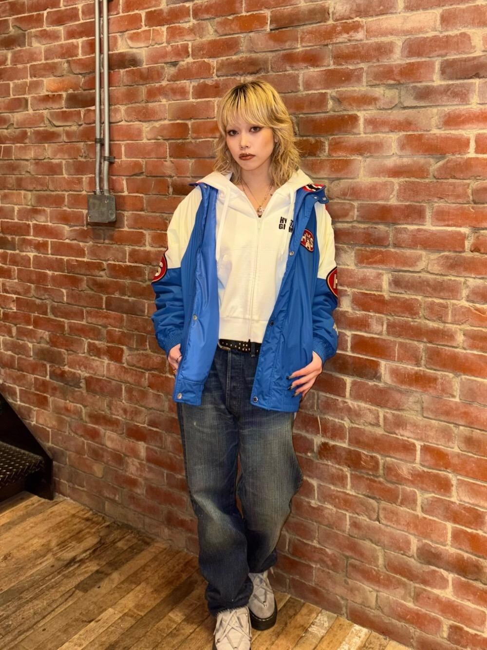 ホワイト系のパーカー、ブルー系のブルゾン、ブルー系のデニムパンツを着用したレディースの秋コーディネートの1枚目の写真