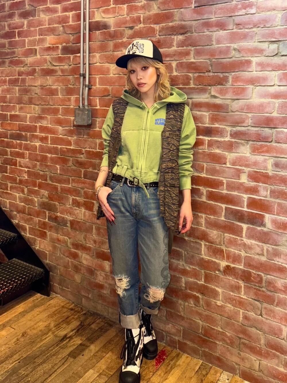 ブルー系のデニムパンツ、グリーン系のベスト、グリーン系のパーカーを着用したレディースの冬コーディネートの1枚目の写真