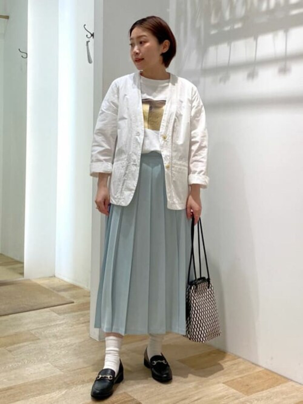 ホワイト系のノーカラージャケット、ホワイト系のTシャツ/カットソー、グリーン系のスカートを着用したレディースの春コーディネートの1枚目の写真