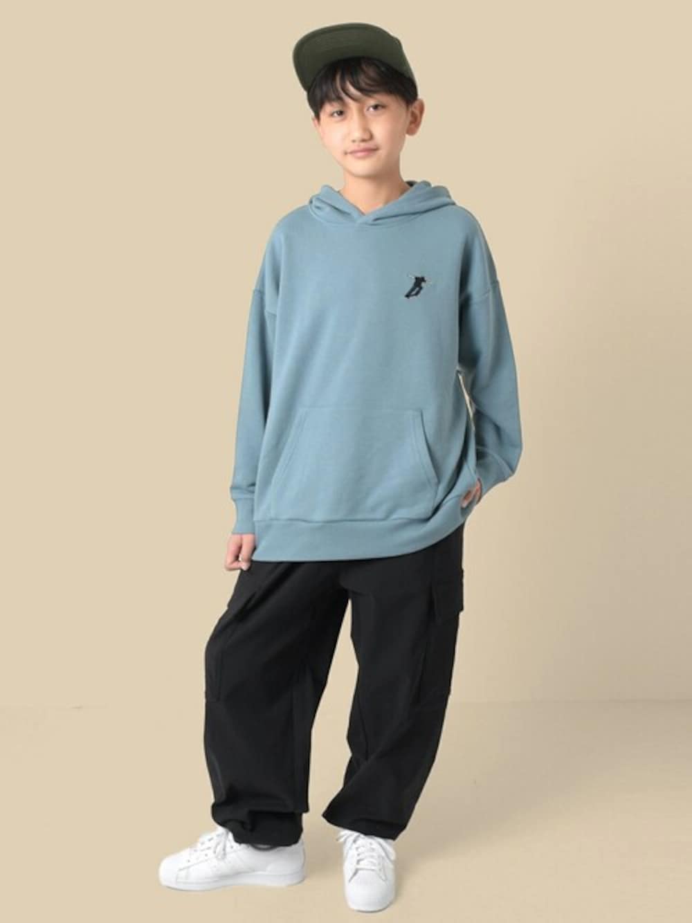 ブルー系のパーカー、ブラック系のカーゴパンツ、グリーン系のキャップを着用したキッズの冬コーディネートの1枚目の写真