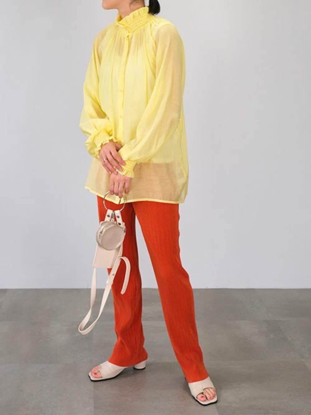 イエロー系のシャツ/ブラウス、オレンジ系のその他パンツ、ホワイト系のショルダーバッグを着用したレディースの春コーディネートの1枚目の写真