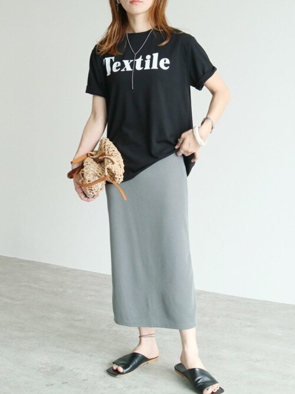 グリーン系のスカート、ブラック系のTシャツ/カットソーを着用したレディースの夏コーディネートの1枚目の写真