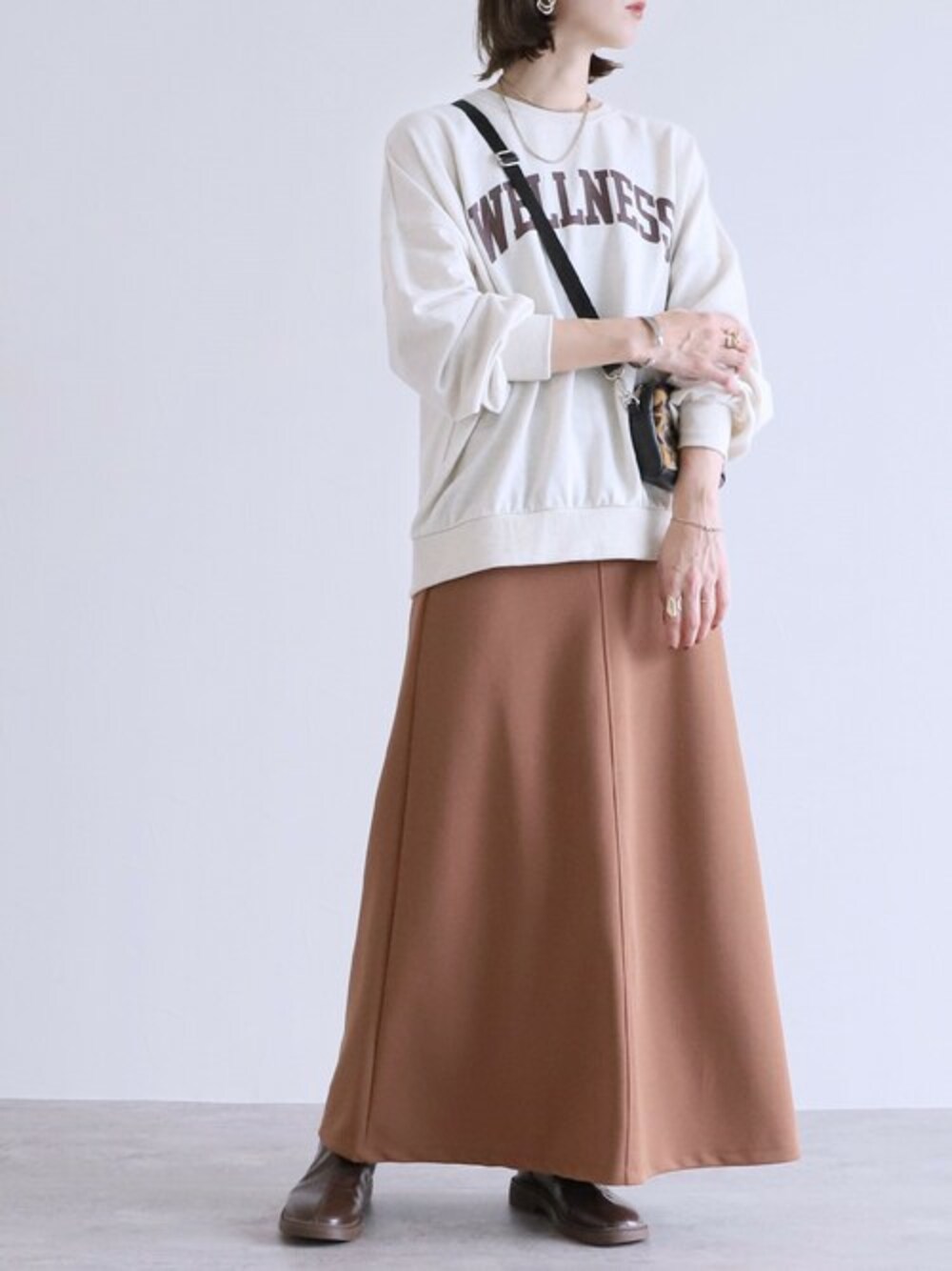 ブラウン系のスカート、ベージュ系のスウェットを着用したレディースの秋コーディネートの1枚目の写真