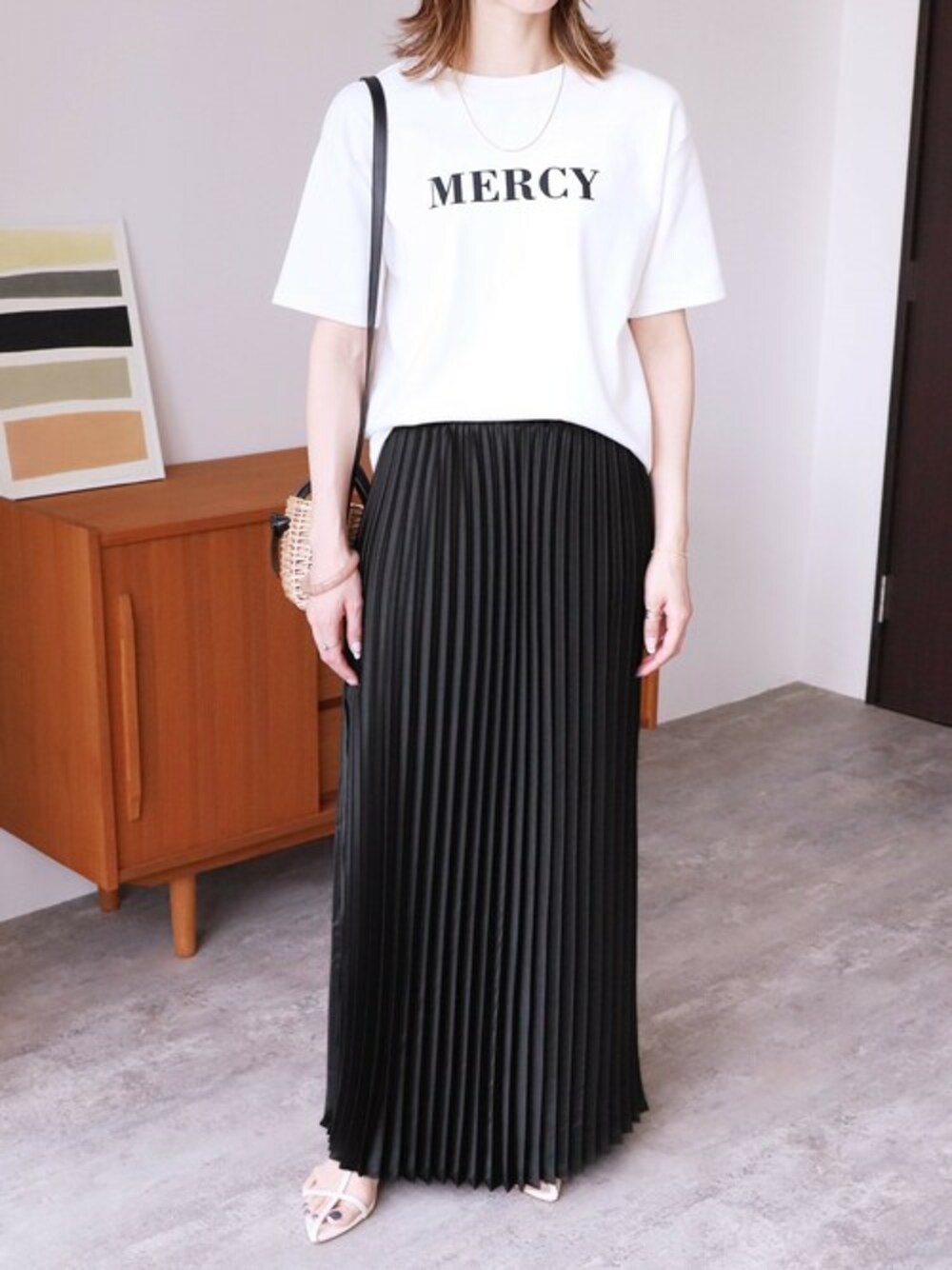 ブラック系のスカート、ホワイト系のTシャツ/カットソーを着用したレディースの春コーディネートの1枚目の写真