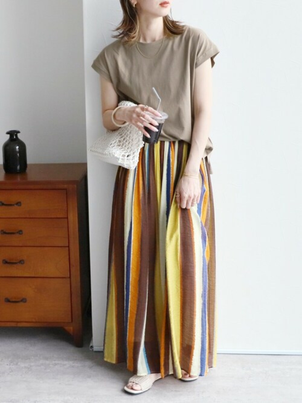 ベージュ系のTシャツ/カットソー、オレンジ系のスカートを着用したレディースの夏コーディネートの1枚目の写真