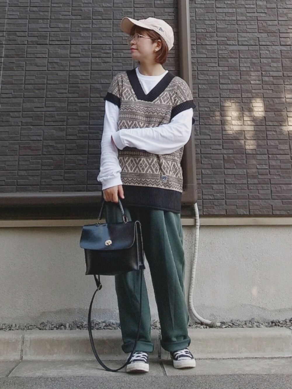 ベージュ系のベスト、グリーン系のスウェットパンツ、ブラック系のショルダーバッグを着用したレディースの秋コーディネートの1枚目の写真